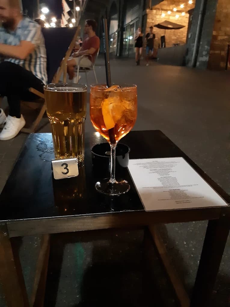 Spritz et bière posés sur une table de la terrasse des Arches, en soirée.