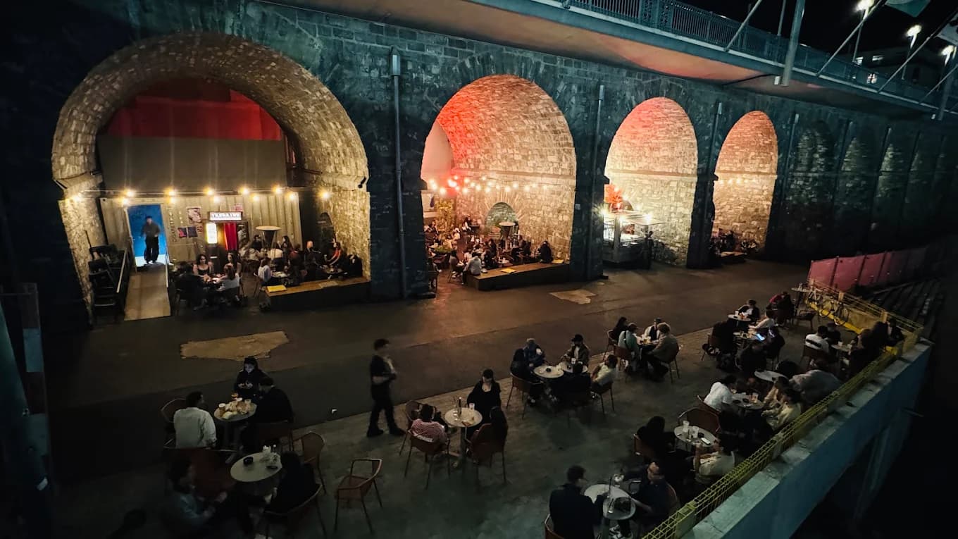 Sous les voûtes en pierre des Arches : tables et public un soir de concert, Lausanne.